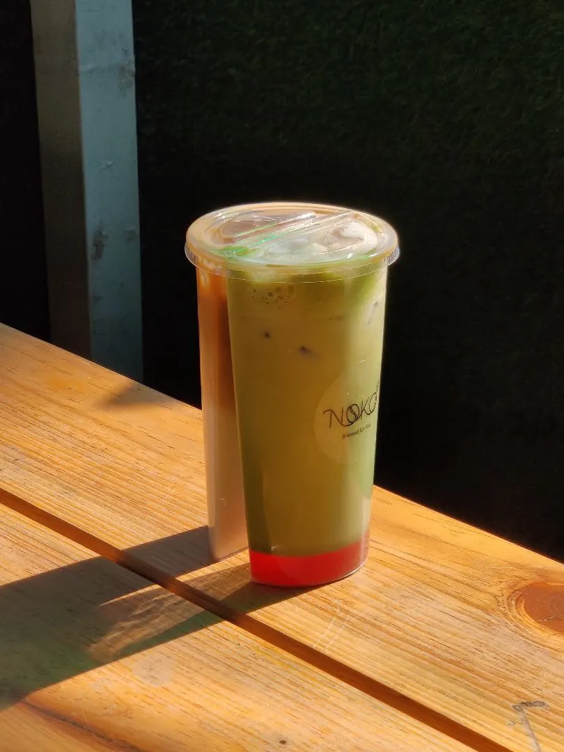 A sunlit Noko matcha latte on a wooden table
