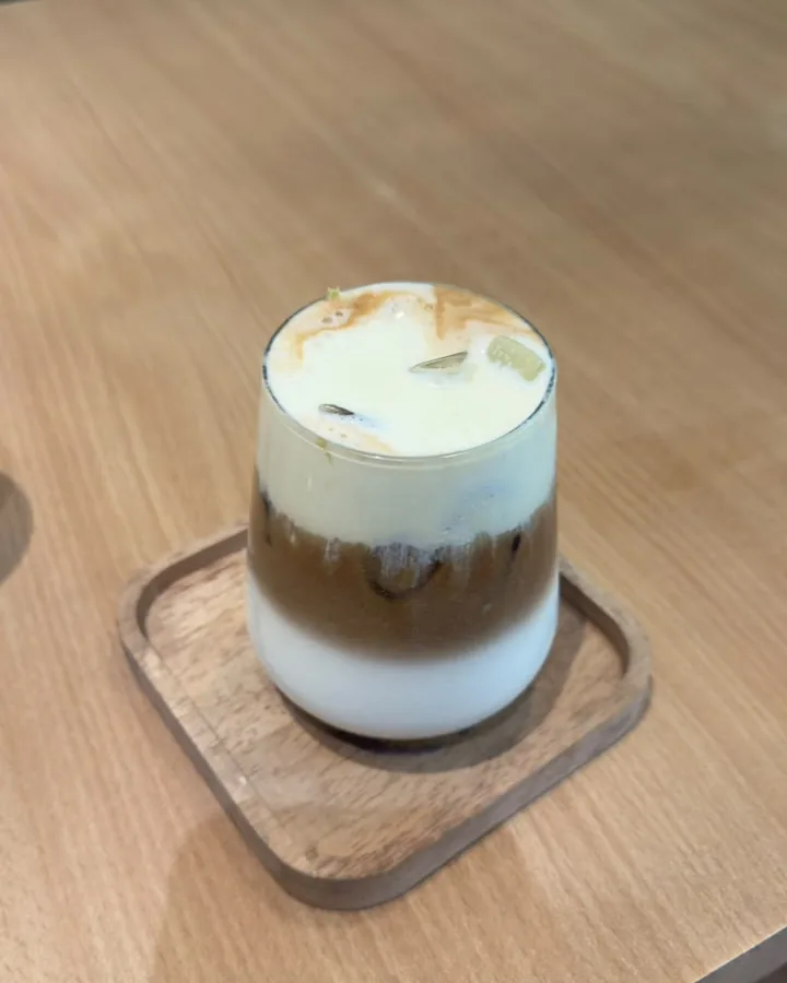 A layered iced latte on a wooden tray