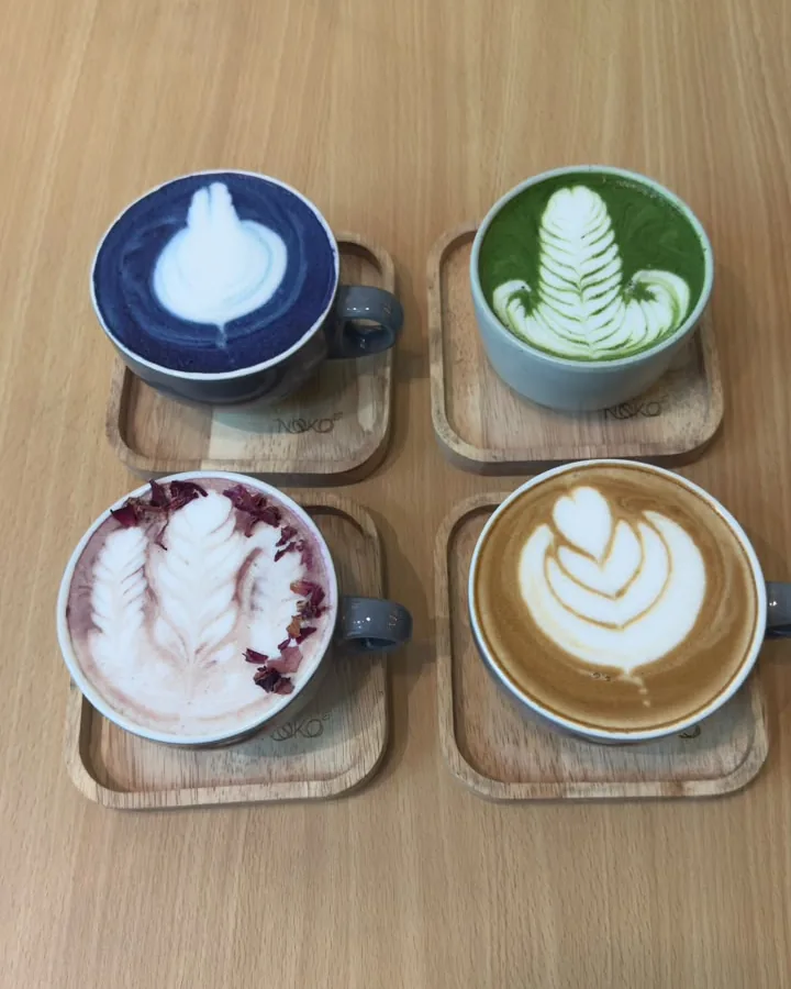 Four latte-art cups on a wooden table