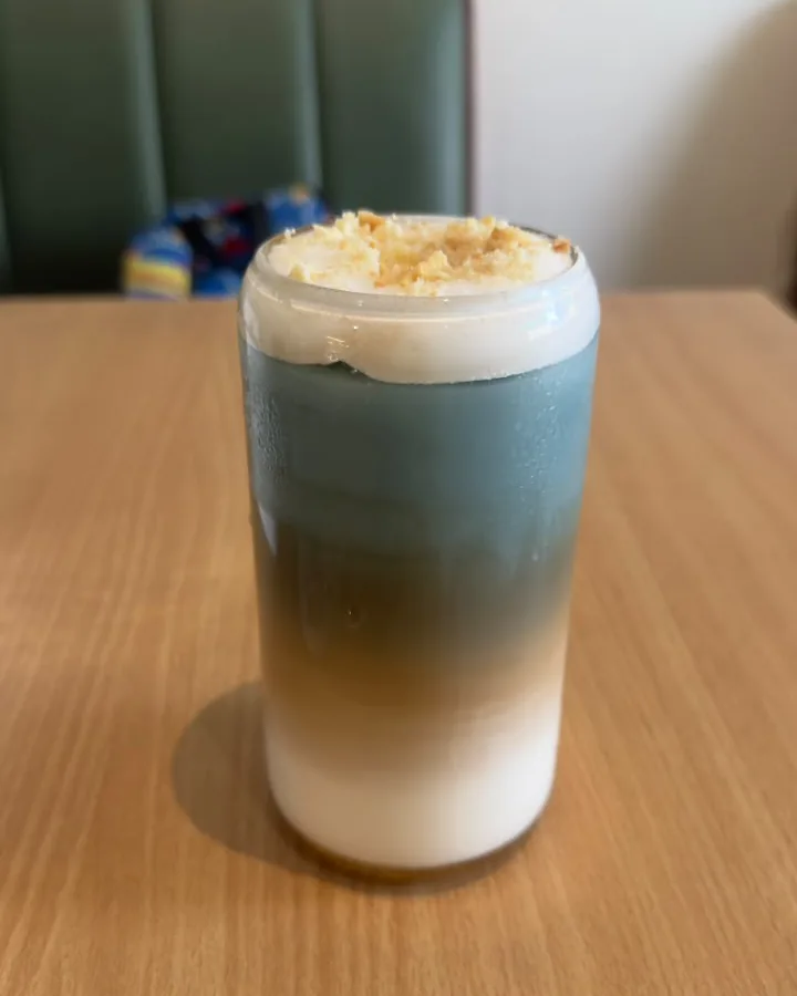 A layered blue and espresso latte topped with crumble