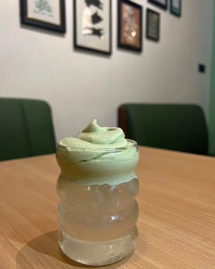 A pale green whipped drink in a ribbed glass